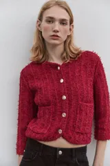 Chaqueta roja de tweed con cuello redondo, manga francesa, bolsillos delanteros y cierre frontal con botones dorados.