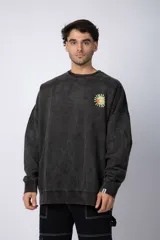 Buzo negro de cuello redondo y corte oversize en tela friza con teñido artesanal y estampa de sol sonriente en el pecho.