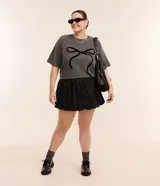Remera gris de algodón con cuello redondo y manga corta. Presenta un estampado central de un lazo negro.
