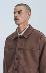 Chaqueta marrón de paño con cuello clásico, cierre frontal con botones, dos bolsillos de parche en el pecho y corte holgado.