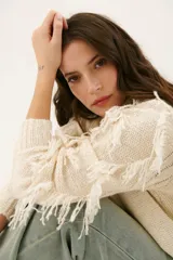 Sweater color arena de tejido de punto con cuello redondo y mangas largas con flecos.