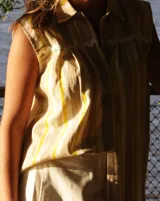 Camisa sin mangas con cuello clásico y estampado a rayas verticales en tonos beige y amarillo.