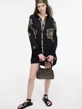 Camisa negra con bordados dorados, cuello camisero, botones frontales y bajo irregular.