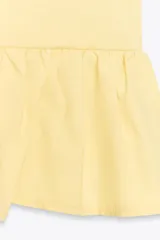 Top amarillo de escote pico y manga corta abullonada con elástico. Detalle de combinación de tejidos a tono y bajo con volante. Cierre frontal con lazadas.