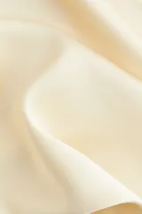 Pollera midi color crema, con leve brillo y caída suave. Modelo de tiro alto con elástico oculto en la cintura y leve vuelo en el bajo.