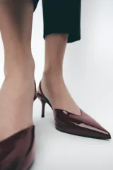 Zapato destalonado acharolado color borgoña, con escote en pico, cierre con tira trasera ajustable, tacón fino y punta fina.