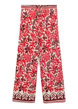 Pantalón de viscosa con estampado floral en tonos rojo, blanco y marrón. Tiene cintura elástica con cordón ajustable, corte recto y dos bolsillos laterales.