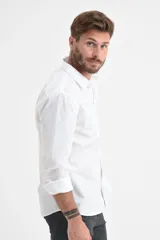 Camisa blanca de manga larga con cuello clásico y cierre frontal con botones.