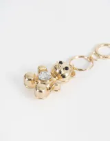 Llavero dorado con dije de oso de peluche con un cristal en forma de corazón en el pecho.
