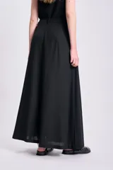 Falda larga negra de lino, corte recto y bolsillos laterales.