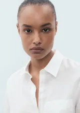 Camisa blanca de lino 100%, con diseño recto, cuello camisero, manga larga con puños abotonados y bolsillo de parche en el pecho.