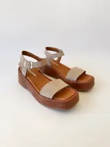 Sandalias con plataforma color beige, con tira ancha sobre los dedos y tira con hebilla al tobillo.