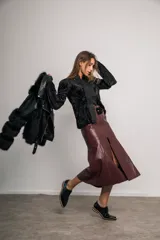 Falda midi color marfil de cuerina, con cierre metálico frontal, cinturón con lazo y abertura delantera.