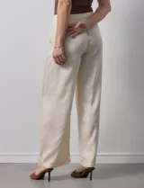 Pantalón palazzo color crema, marca Nanette, con pretina elastizada, lazo de ajuste y bolsillos delanteros.