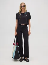 Pantalón de algodón negro, corte holgado y pierna ancha con pretina elástica. Presenta rayas bicolor al costado en blanco y celeste. Calce de tiro alto.
