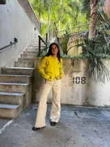 Saco de punto color amarillo, con cuello redondo con volados y cierre frontal con botones.