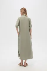 Vestido camisero midi negro de corte holgado, con cuello camisero, mangas cortas con trabillas, cierre frontal con botones, bolsillo en el pecho y bolsillos laterales.