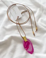 Collar con cordón de cuero sintético color beige que se ata al cuello y dije de ágata rosa con borde blanco y aplique dorado.