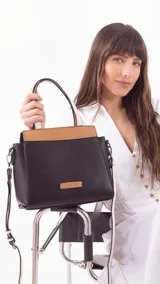 Cartera negra con detalles en color suela, con bolsillo principal con cierre y varios bolsillos interiores. Incluye un bolsillo posterior, asas cortas y correa extensible.