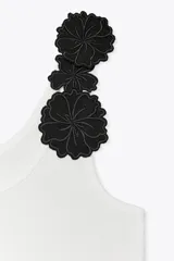 Top blanco de algodón con escote redondo y tirantes decorados con apliques de flores negras.