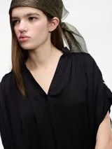 Blusa negra de manga corta con escote en V y bordados en la espalda.