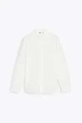 Camisa blanca de algodón con cuello con volantes y mangas largas con puños fruncidos.