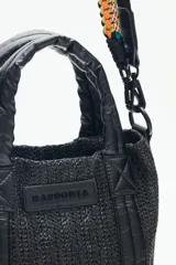 Cartera tote mini color negro, confeccionada en tejido tipo rafia. Cuenta con bolsillos internos, dos correas desmontables y abertura superior con cierre.