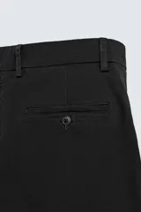 Pantalón chino color beige, de corte recto y tiro medio. Confeccionado en tejido de algodón con elasticidad, con bolsillos laterales y traseros de vivo. Cierre frontal con cremallera y botón.