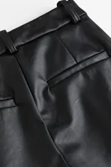 Pantalón de vestir negro de cuero sintético, de tiro alto, corte ancho y pinzas.