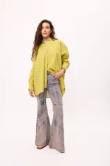 Camisa oversize a rayas verticales color amarillo y blanco, con cuello camisero, manga larga y cierre frontal con botones.