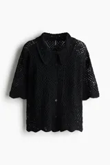 Camisa negra de manga corta en punto pointelle suave, con cuello y botones adelante. Ribete festoneado en mangas y bajo.