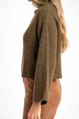 Sweater de punto acanalado color marrón, con cuello alto tipo polera y mangas largas de corte ancho. Posee un diseño oversize confeccionado en mezcla de lana.