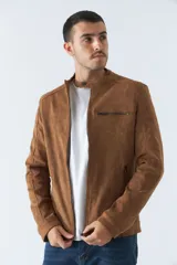 Campera de gamuza color beige con cuello mao, cierre frontal con cremallera, bolsillos laterales con cierre y puños con botón.