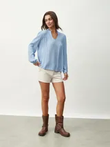 Blusa celeste con cuello mao y escote en V, de mangas largas con puños elásticos.