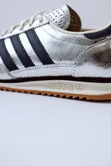 Championes Adidas SL 72 plateados con detalles en azul marino y suela de goma marrón.