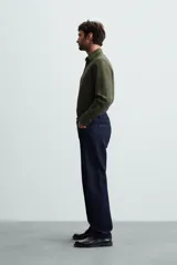 Camisa negra de manga larga con cuello italiano y cierre frontal de botonadura. Presenta un tejido con estructura de fácil cuidado.