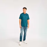 Remera tipo polo color petróleo con cuello de punto acanalado, puños de manga de punto plano y parche de silicona con el logo de Cat en el lado izquierdo del pecho.