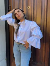 Camisa negra con cuello clásico, mangas largas abullonadas con puños elásticos y cierre frontal con botones.