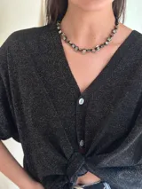 Collar corto con cuentas de nácar con subtono negro, mostacillas y cristales checos. Se cierra con cadena de acero quirúrgico y ganchito para regular el largo.