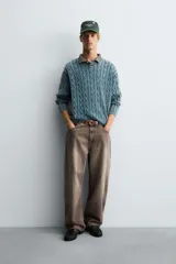 Jersey de algodón de corte relajado, color azul verdoso lavado, con cuello redondo amplio y manga larga. Presenta un tejido de punto con estructura de trenzas verticales.