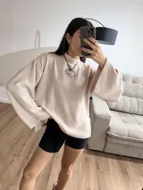 Sweater rosa de tejido de punto acanalado, con cuello alto y mangas anchas.