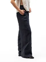 Pantalón largo de vestir color azul marino, corte ancho y tiro alto con pliegues frontales. Presenta bolsillos laterales inclinados y bolsillos traseros ribeteados. La cintura es ajustable con elástico en la parte trasera.