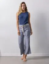 Pantalón de lino a rayas verticales azules y blancas, con corte ancho, pretina con pasadores, cierre y botones. Incluye cinto de soga con nudo.