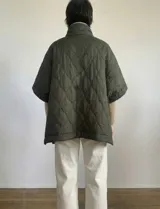 Poncho acolchado color mostaza con cuello alto y abertura frontal con cierre. Presenta un patrón capitoné de formas ovaladas y bolsillos delanteros.