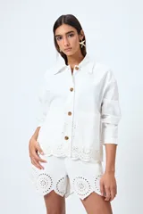 Sobrecamisa blanca de algodón con cuello camisero, botones marrones y detalles de encaje calado en el ruedo.