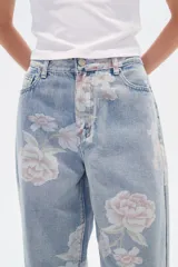 Pantalón de jean celeste con estampado de flores rosas, corte recto y tiro medio.
