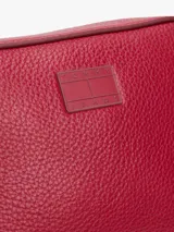 Bandolera Tommy Jeans roja con acabado granulado, cierre de cremallera, correa ajustable y logo tonal en el frente.