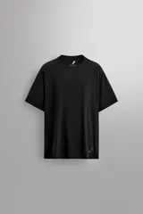 Camiseta deportiva negra de cuello redondo y manga corta, confeccionada en tejido ligero y elástico. Tiene aberturas laterales en el bajo y logo estampado.