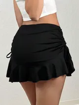 Minifalda negra ajustada al cuerpo con volado inferior y laterales ajustables con cordones.