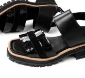 Sandalias de cuero color crudo con dos tiras horizontales en el empeine, una de cuero liso y otra con detalle dorado. Suela track color beige.